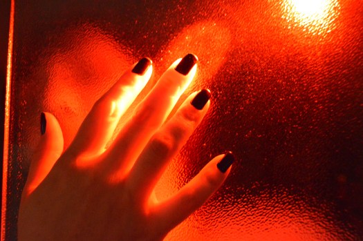 Marcela's hand touching a glass wall.